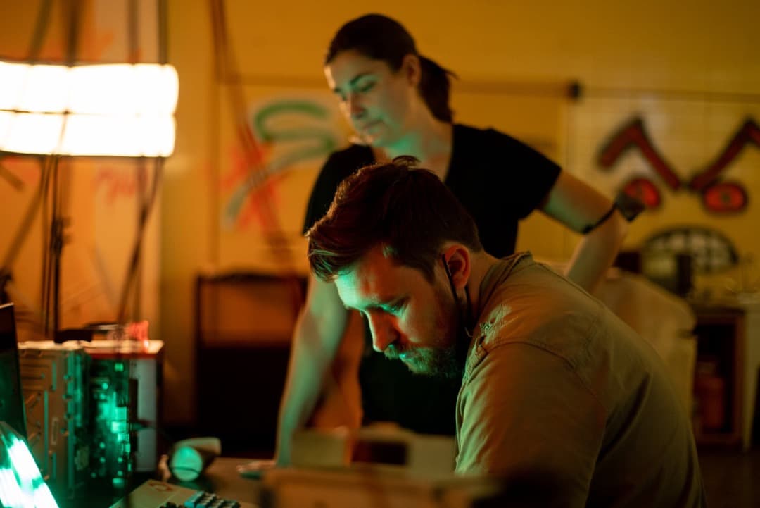 Behind the scenes photo 14 from Clone Cops production showing 1st ad nate eggert and key pa jenny gill preparing for a scene